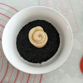 取一小碗盛装黑芝麻芝麻，将面团底部粘上黑芝麻