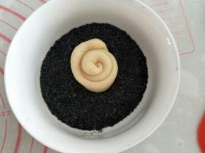 取一小碗盛装黑芝麻芝麻，将面团底部粘上黑芝麻