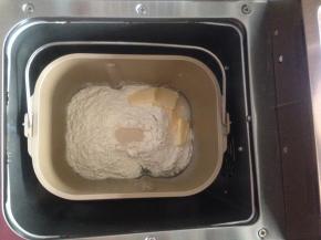 加入奶粉、面粉和黄油，在面粉顶端加入酵母，将面包桶放入到面包机内