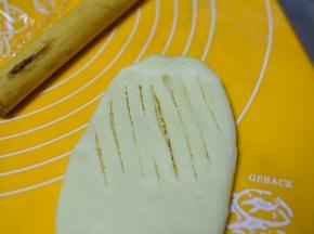 在将包好椰蓉的面团擀成长条状，在一侧划出一厘米宽的道