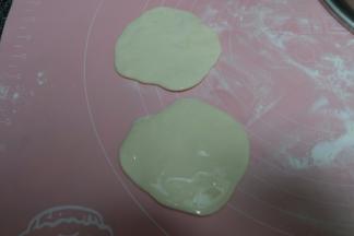 静置好的面团用擀面杖稍微擀一下，像饺子皮大小，十个面团依次擀好以后，在其中五个上面抹上油；