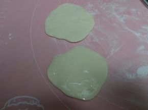 静置好的面团用擀面杖稍微擀一下，像饺子皮大小，十个面团依次擀好以后，在其中五个上面抹上油；