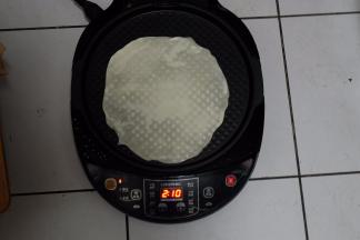 电饼铛预热，上下盘加热，底盘刷一层油，把饼放进去，因为饼很薄，一遇热，就会变色了；