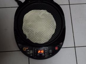 电饼铛预热，上下盘加热，底盘刷一层油，把饼放进去，因为饼很薄，一遇热，就会变色了；