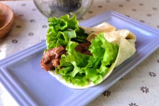 取一张饼，铺上生菜叶，再铺上炒好的牛肉条；