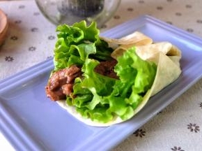 取一张饼，铺上生菜叶，再铺上炒好的牛肉条；