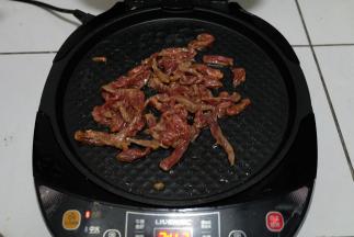 等饼全部烙好以后，电饼饼底盘放一点油，把腌好的牛肉条放进去翻炒，我家不能吃辣，所以没有放辣椒，如果喜欢吃辣的，可以放点辣椒进去，更好吃；