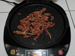 等饼全部烙好以后，电饼饼底盘放一点油，把腌好的牛肉条放进去翻炒，我家不能吃辣，所以没有放辣椒，如果喜欢吃辣的，可以放点辣椒进去，更好吃；