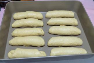 依次卷好所有的面包卷，摆放在烤盘里。放在烤箱里进行二次发酵。二次发酵可以通电使用烤箱发酵功能，也可以不用通电，把面包盘放在中上层，底层再放一个烤盘装满开水，这样烤箱内就有了温度和湿度，也有助于发酵；