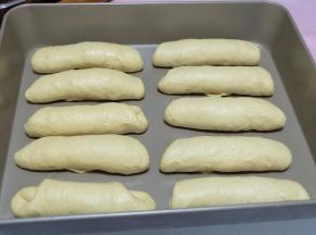 依次卷好所有的面包卷，摆放在烤盘里。放在烤箱里进行二次发酵。二次发酵可以通电使用烤箱发酵功能，也可以不用通电，把面包盘放在中上层，底层再放一个烤盘装满开水，这样烤箱内就有了温度和湿度，也有助于发酵；