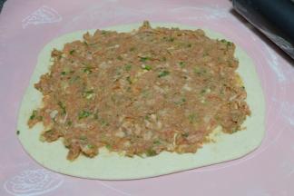 把调好的肉馅取一部分铺在面饼上，尽量摊的均匀一些；