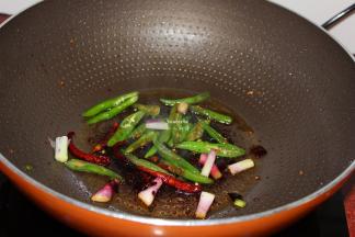 把多余的油倒出来，锅中留小许有，放入辣椒、葱头爆炒香；