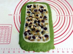 把核桃仁、葡萄干以及蔓越莓均匀铺在麻薯上，轻轻按压下。