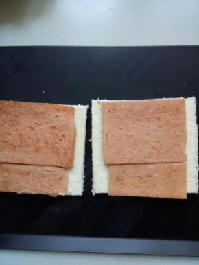 把煎好的午餐肉放在面包片上，其中有一片分一半