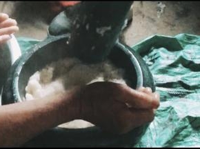 趁热把糯米倒入石臼中捶打，一个人翻糯米，一个打