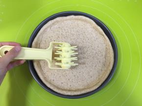 把面团擀成比10寸的披萨盘大一点的圆面片，披萨盘内抹一层融化的黄油，然后放入擀好的面皮，用戳孔器把披萨皮压上孔