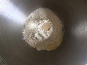 面桶内倒入高筋面粉，中间挖一小孔倒入活性干酵母，盐和糖对角线放置，炼乳倒入，加入清水，启动厨师机和面