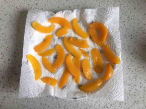 先来处理黄桃罐头，把黄桃从罐头中取出，用厨房用纸吸干水分，把黄桃切片，放一边晾干水分备用