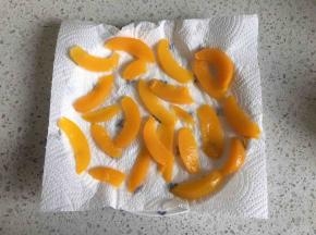 先来处理黄桃罐头，把黄桃从罐头中取出，用厨房用纸吸干水分，把黄桃切片，放一边晾干水分备用