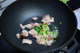 锅中油七成热，加入八角加肉炒香，再加入葱姜蒜各5克，炒至肉段生。