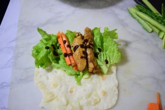 将黄瓜，胡萝卜，鸡肉，生菜，甜面酱将放在饼上