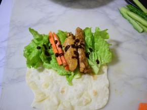 将黄瓜，胡萝卜，鸡肉，生菜，甜面酱将放在饼上