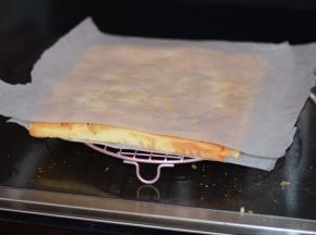 10，烤好的蛋糕要立即取出，震出热气后，在表面垫上一张烘焙纸，然后倒转过来。