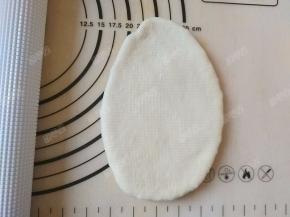 将松弛好的面团用擀面棍擀一上一下擀为椭圆形的牛舌状