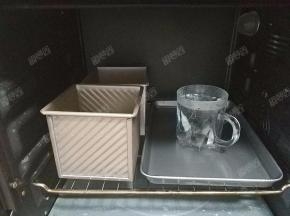 将吐司盒放入烤箱中，再放入一杯温水进行发酵