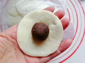 取一块圆面片，中间放上豆沙馅；