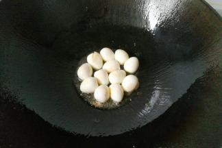 锅中入少许油，下入鹌鹑蛋，再加入一勺料酒翻炒一下；