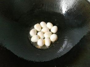 锅中入少许油，下入鹌鹑蛋，再加入一勺料酒翻炒一下；