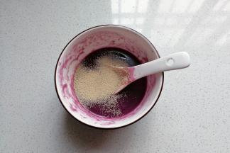 接着做紫面团：先将紫薯粉用热水化开放温凉后加入酵母拌均匀；