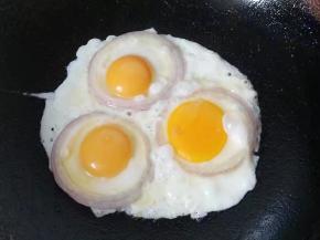然后在洋葱圈中打入鸡蛋，小火煎一会儿后用手拈一点点盐均匀的洒在上面；（洋葱最好挑大个，鸡蛋尽量挑小个，我家只有个小号洋葱了）