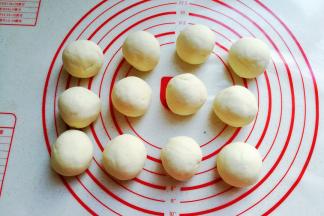 再把发酵好的面团取出挤压排气，然后分成12个均匀的小剂子滚圆，盖保鲜膜静置10分左右；