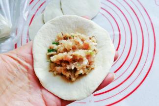 取一份面皮放在左手上，再放入适量肉馅；