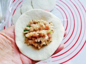 取一份面皮放在左手上，再放入适量肉馅；