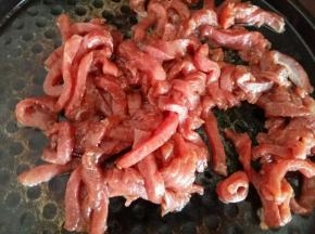 热锅凉油，倒入腌制好的牛肉翻炒。