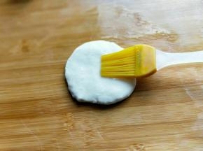 取一块面团，用掌心压扁，刷上一层玉米油。