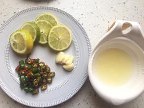 将一个柠檬榨汁，一个切片，线椒切成小圈，蒜压扁