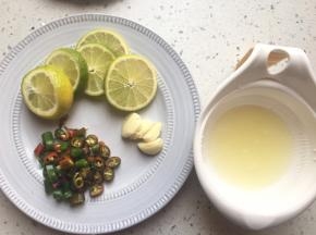 将一个柠檬榨汁，一个切片，线椒切成小圈，蒜压扁