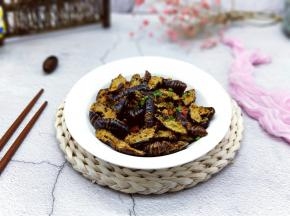 炸好的蚕蛹捞出，撒上葱花。