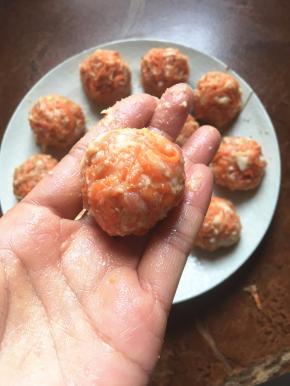 手上沾少许清水抓起少许胡萝卜肉末双手交换团成丸子。
