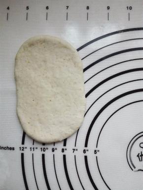 取一个醒发后的面团压扁，擀成椭圆形