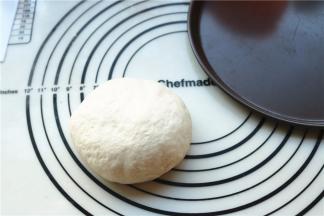 发酵完成的面团排出气体，再次揉圆，准备好披萨盘。