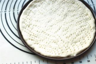 面团擀成披萨盘大小，放入披萨盘，扎出孔洞。