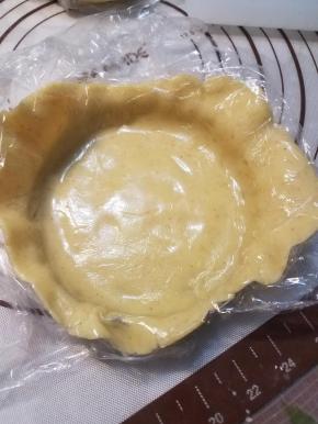 揭掉一面的保鲜膜，将另一面有保鲜膜的面朝上盖在模子里。用手按压，使饼皮跟模子紧密的贴合在一起。