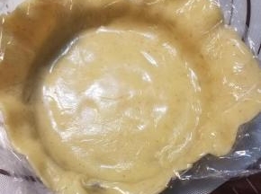 揭掉一面的保鲜膜，将另一面有保鲜膜的面朝上盖在模子里。用手按压，使饼皮跟模子紧密的贴合在一起。