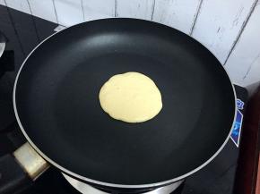 平底锅小火加至六七成热时，舀一勺面糊从中间滴落成圆形