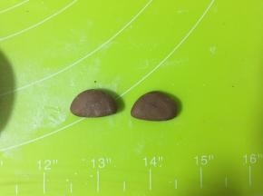 取一个可可小面团，按压成圆形，中间切开，作为耳朵